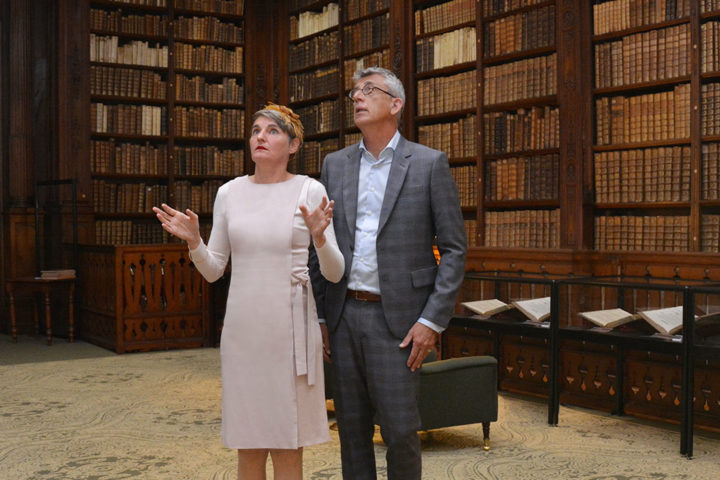 Homme et femme regardant en l’air, dans une pièce entourée de bibliothèques