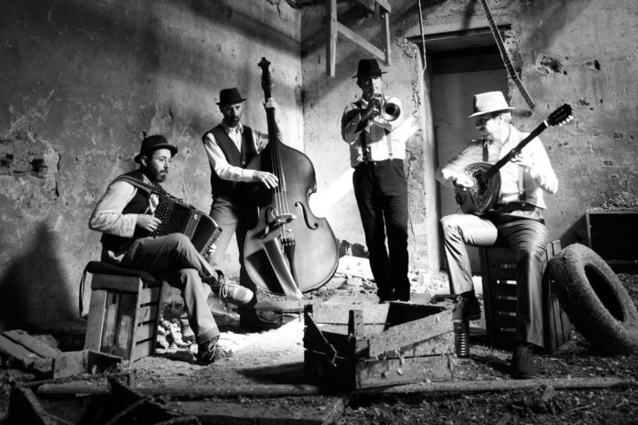 photo noir et blanc d’un quatuor de musiciens (accordéon, contrebasse, trompette, banjo)